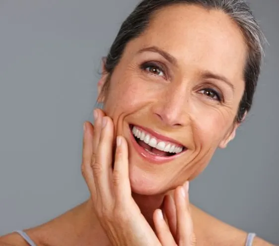 A woman smiling with her hand on her cheek