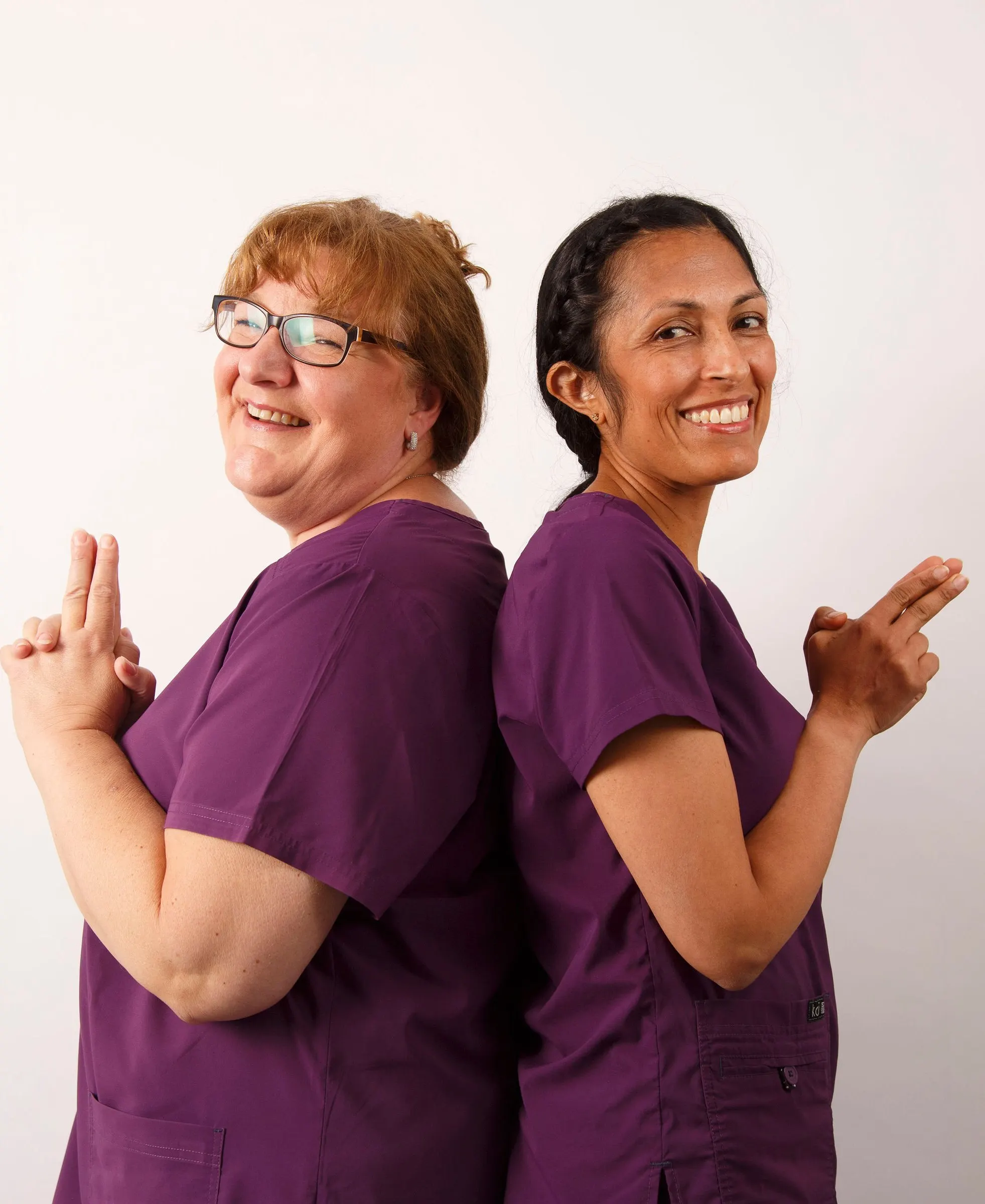 Consultant orthodontists Anne-Marie Smith and Anjli Patel back to back, smiling