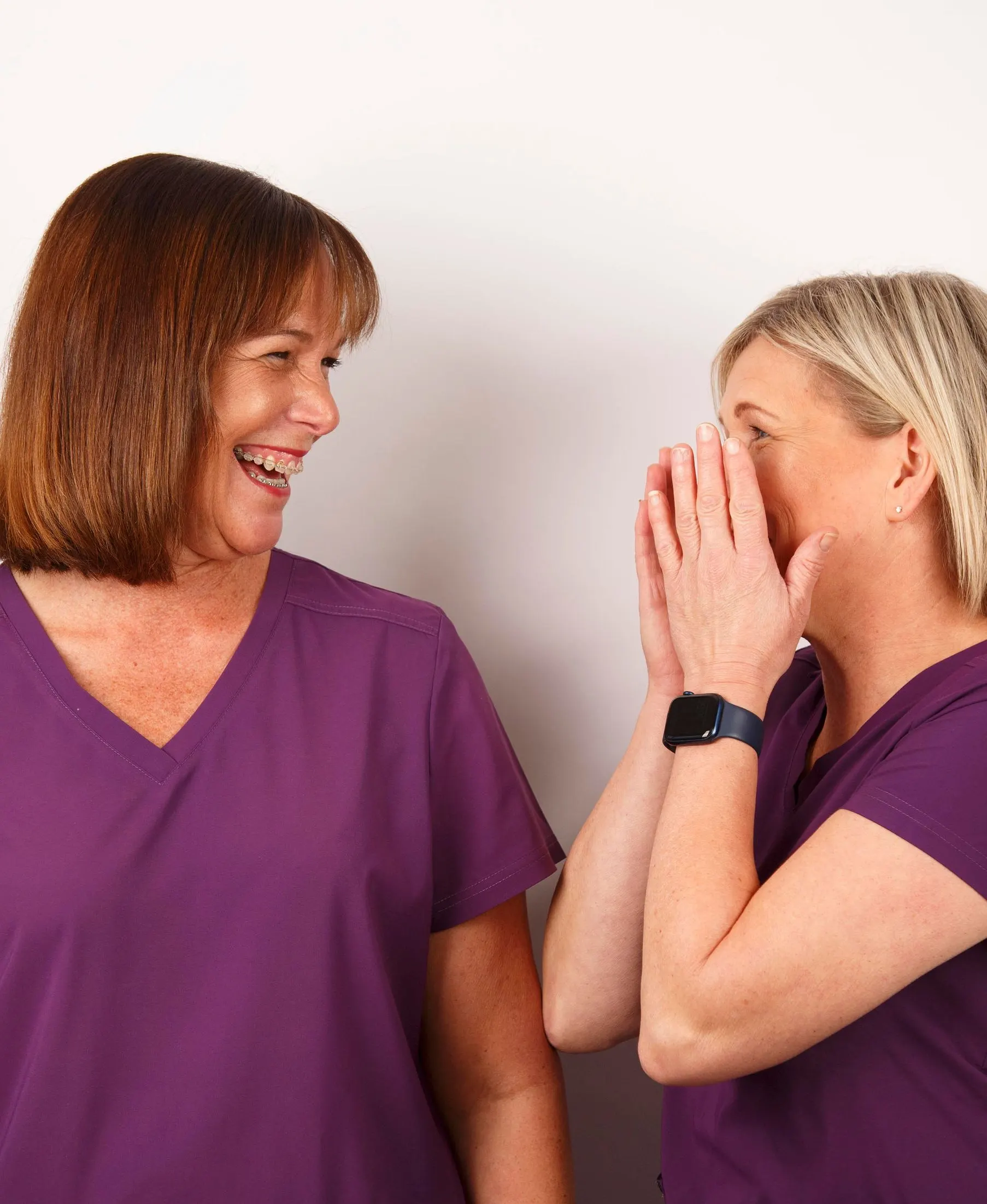 Two members of the No1 team in purple scrubs laughing