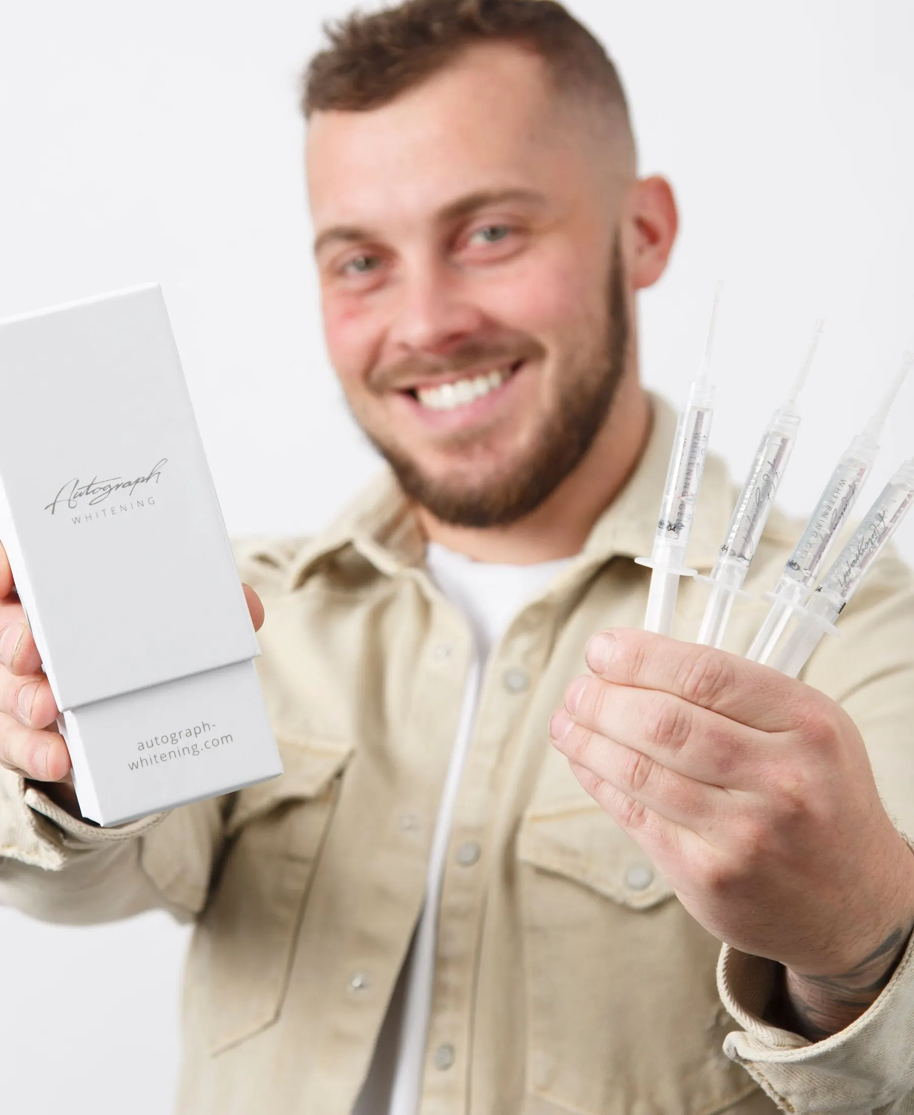 A patient holding a home teeth-whitening kit and smiling