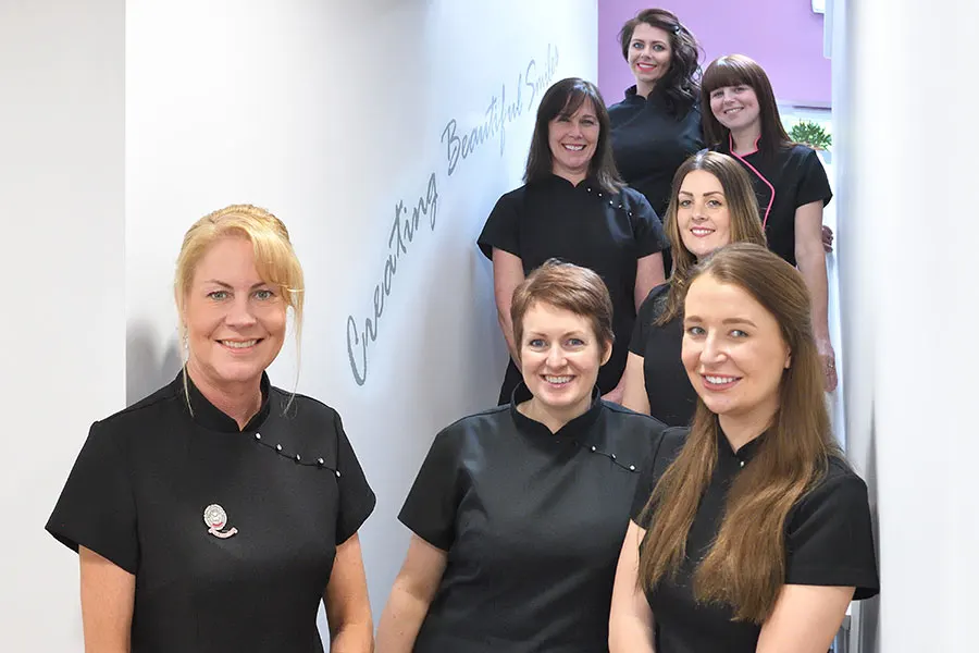 Members of the team by the ‘creating beautiful smiles’ wall